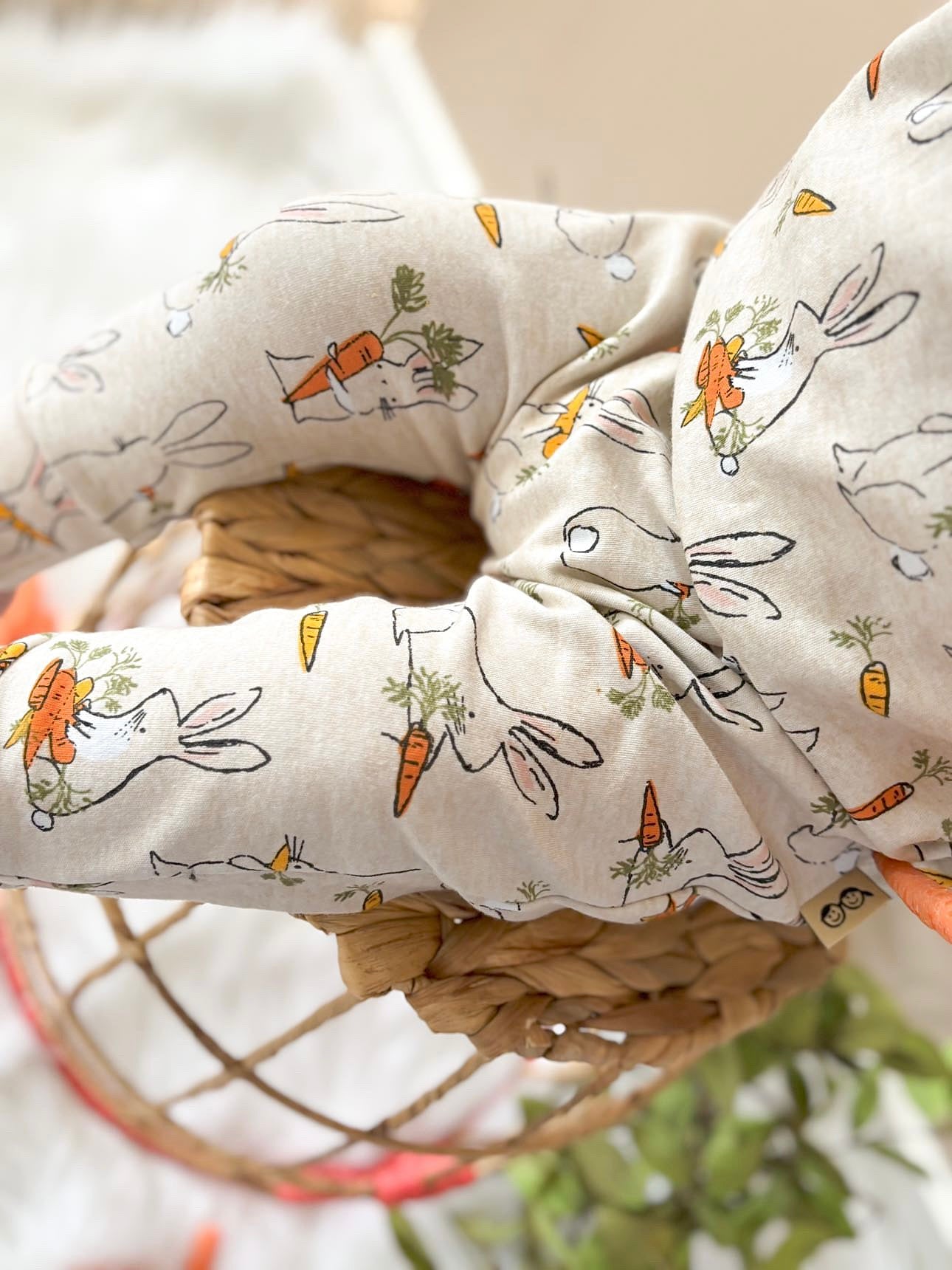Soft beige baby romper with hand-drawn bunny and carrot prints, made from cozy stretch fabric for all-day comfort.