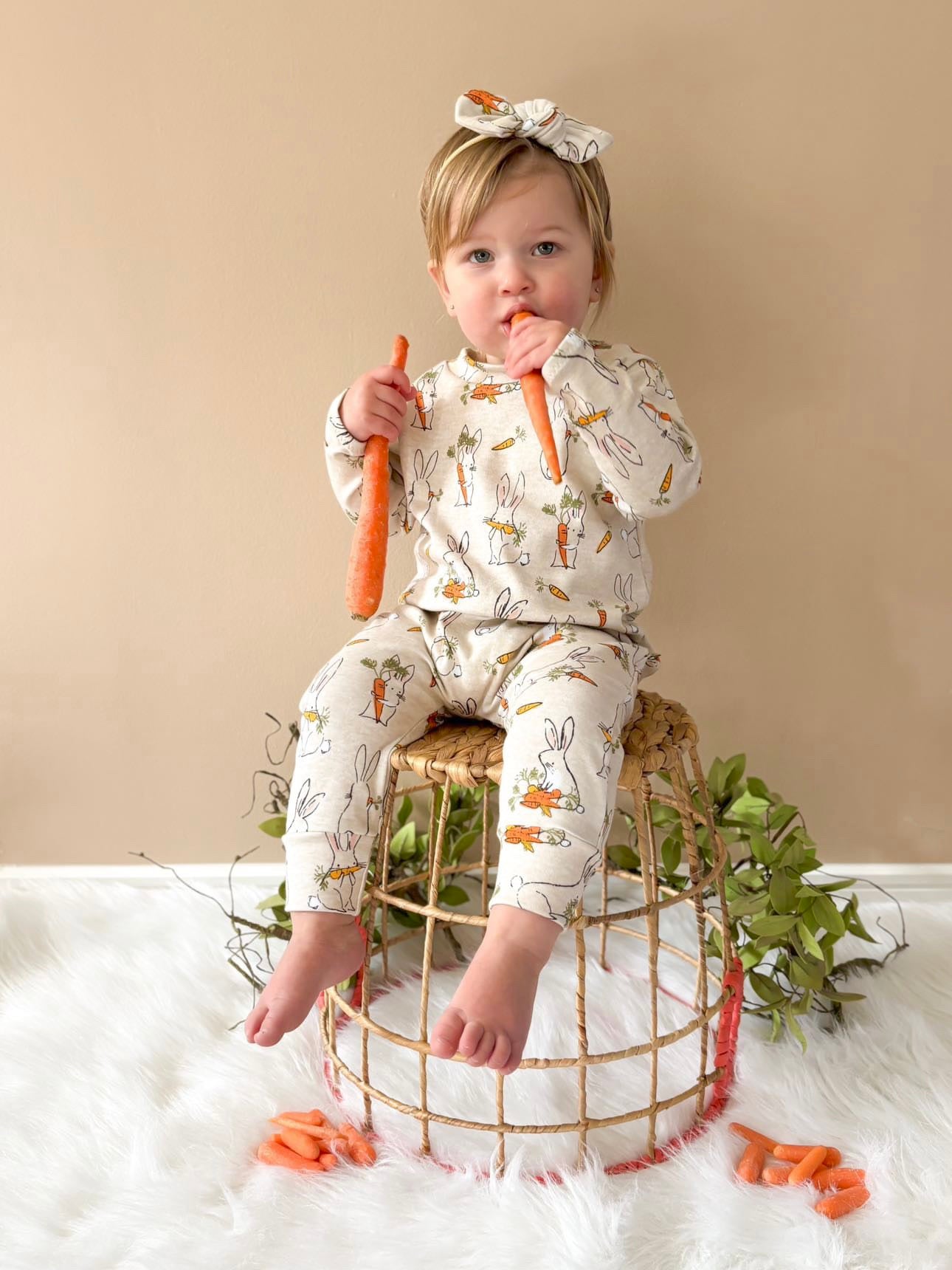 Cute toddler in a long-sleeve Easter bunny romper, enjoying fresh carrots, making it a must-have baby Easter outfit.
