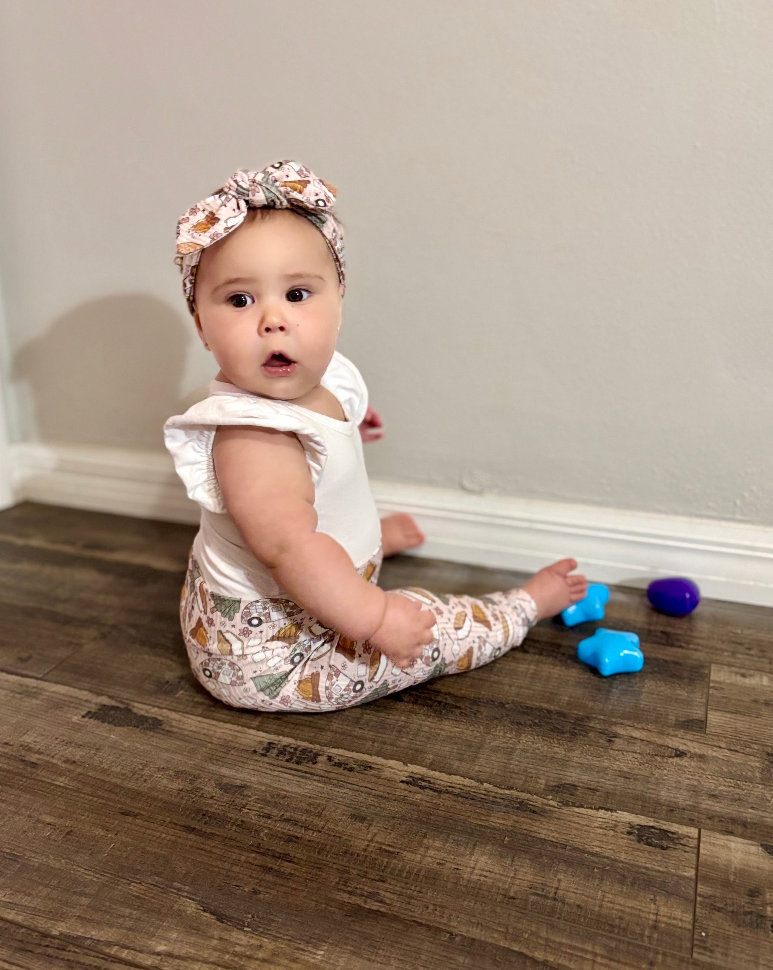 Baby wearing matching leggings and headband in cozy camping print.