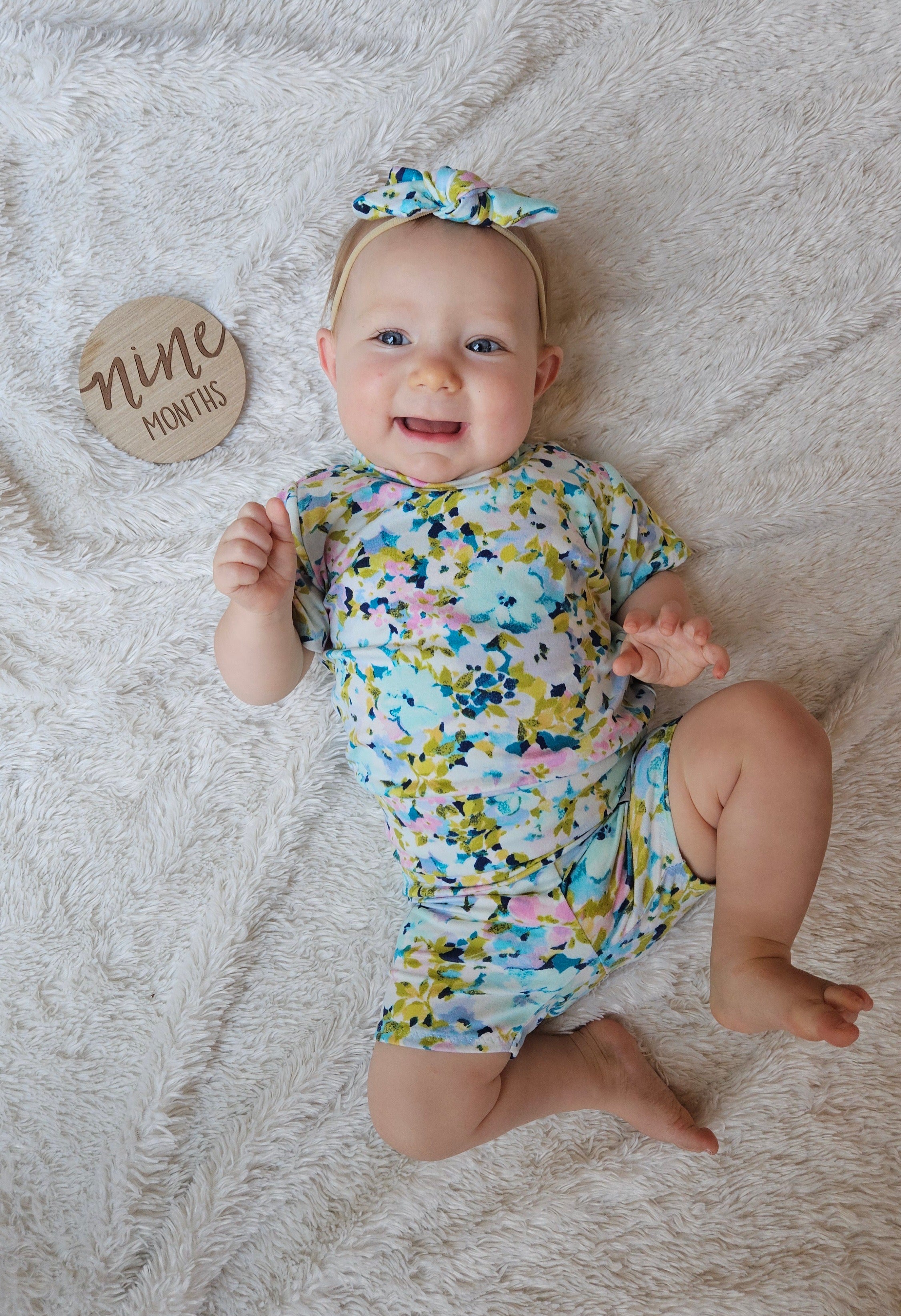 Baby in a floral lounge set on a textured surface with a &