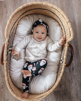 Baby in a wicker Moses basket with white bedding