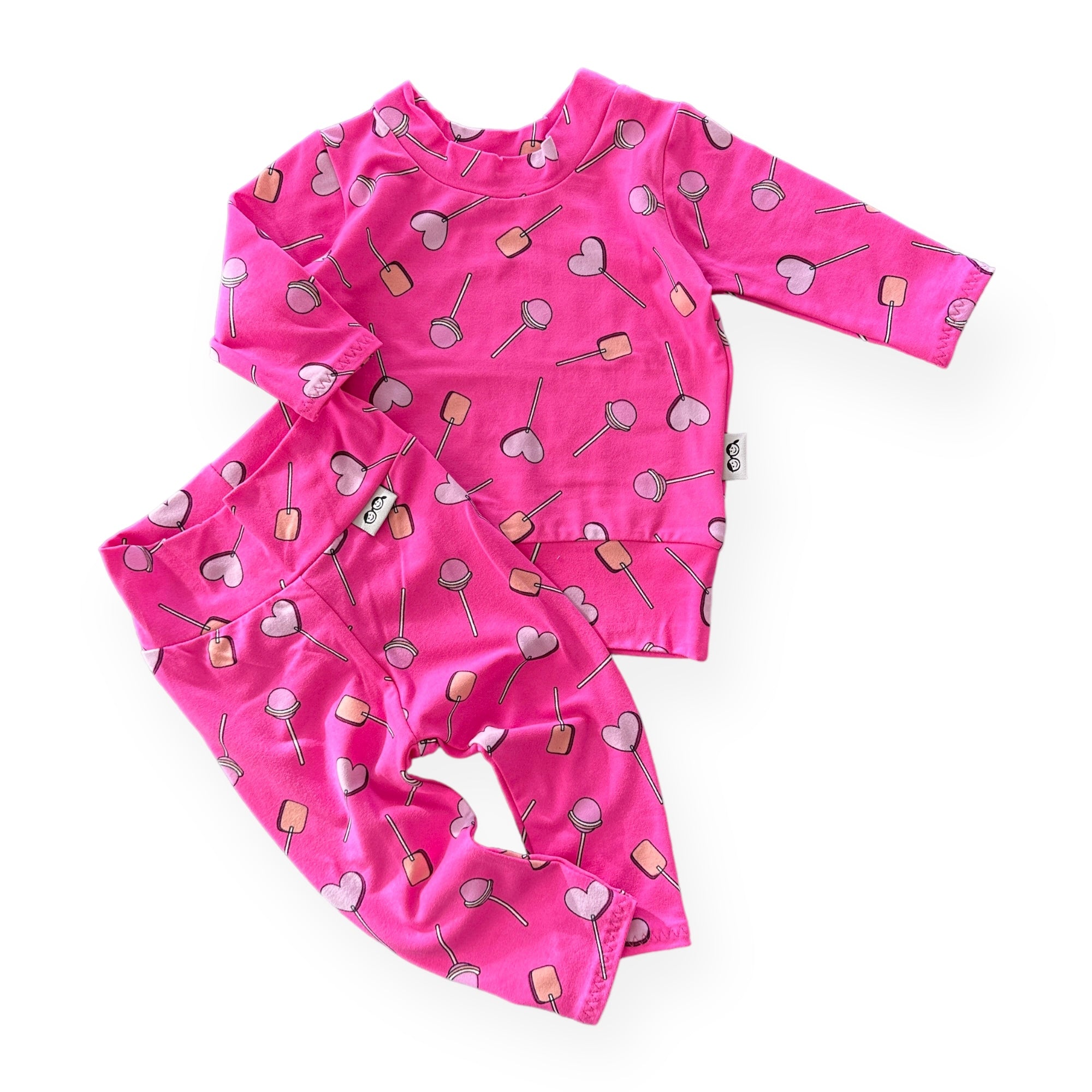 Handmade baby and toddler outfit featuring a long-sleeve top and matching leggings in a vibrant pink lollipop and heart pattern. Perfect for Valentines day or everyday wear. Available in sizes preemie to 4T.