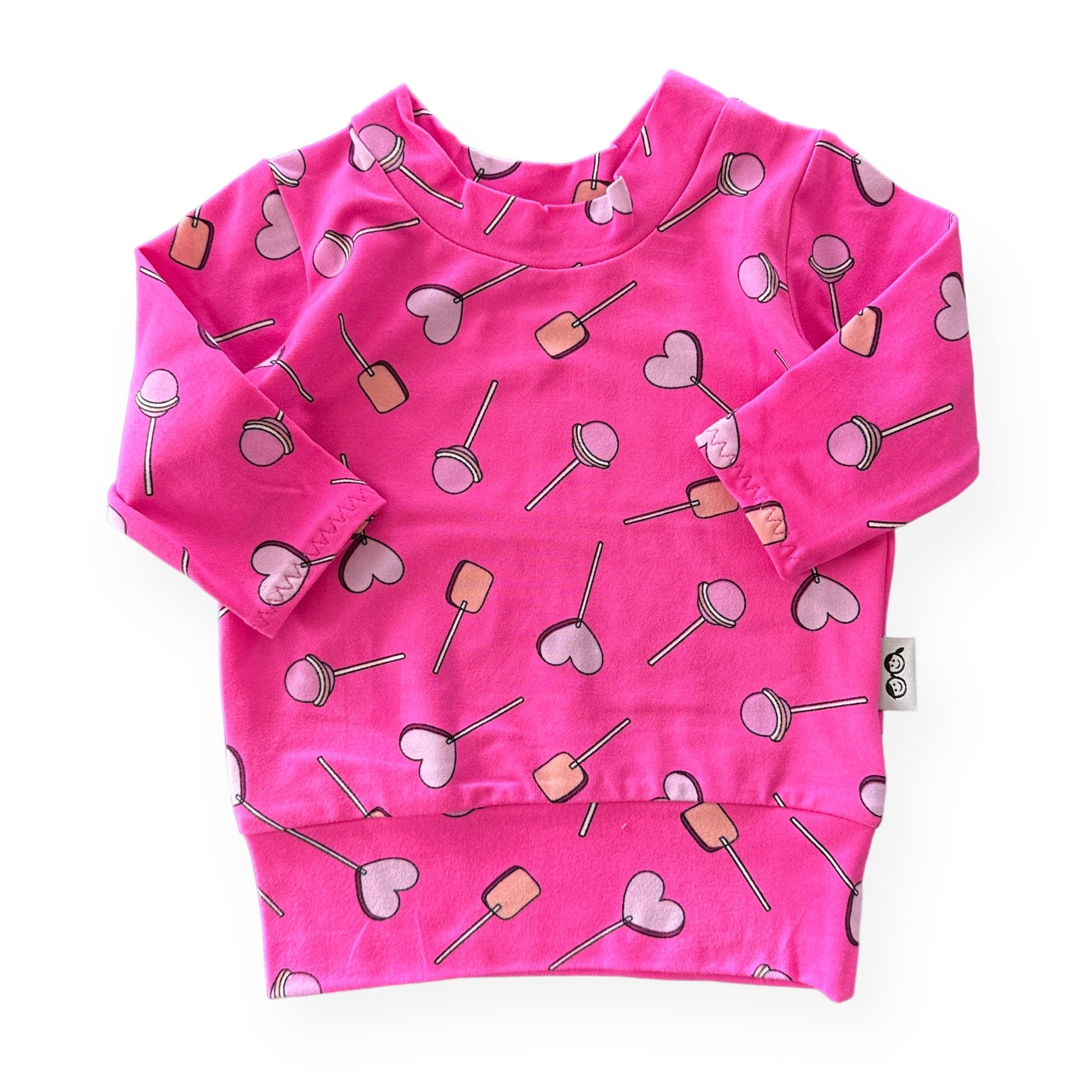 Handmade baby and toddler long-sleeve top featuring a vibrant pink lollipop and heart design. Soft, cozy, and perfect for pairing with leggings or pants for a playful yet comfortable look. Available in sizes preemie to 4T.