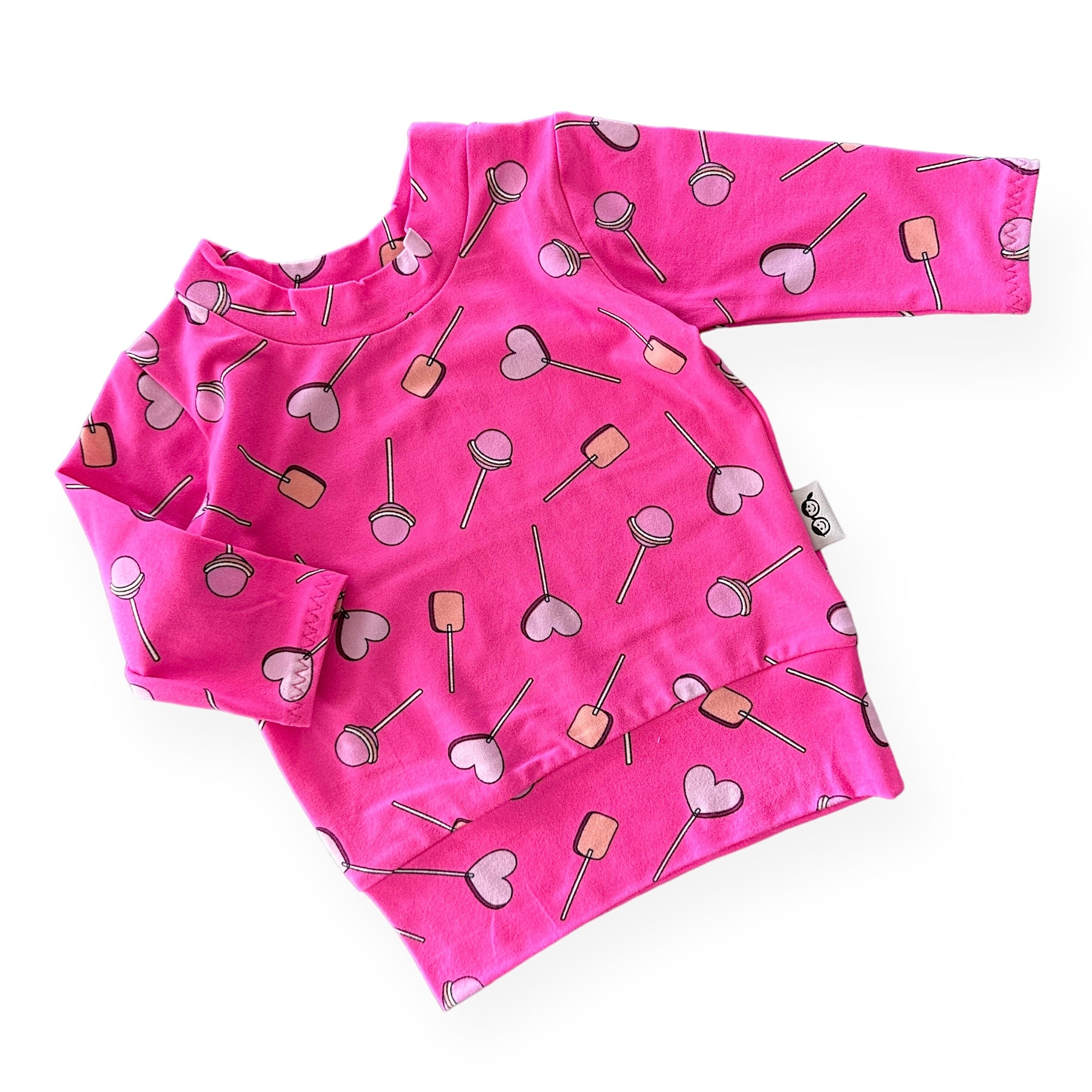 Handmade baby and toddler long-sleeve top featuring a vibrant pink lollipop and heart design. Soft, cozy, and perfect for pairing with leggings or pants for a playful yet comfortable look. Available in sizes preemie to 4T.