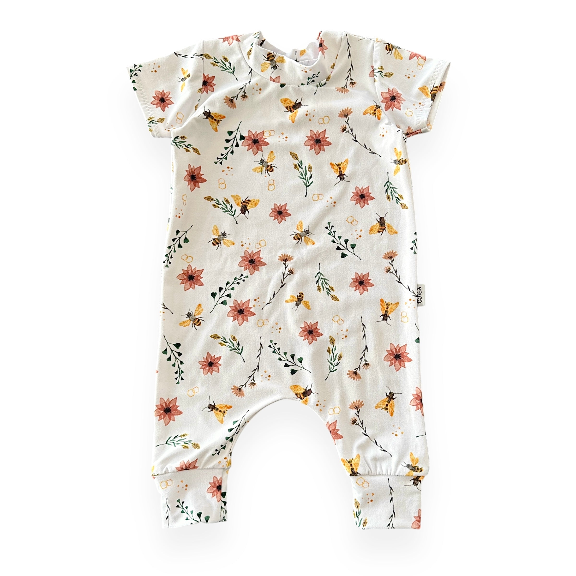 Cream baby romper with yellow bees, coral flowers, green leaves, and honeycomb accents – soft stretch fabric, short sleeves, flat lay.