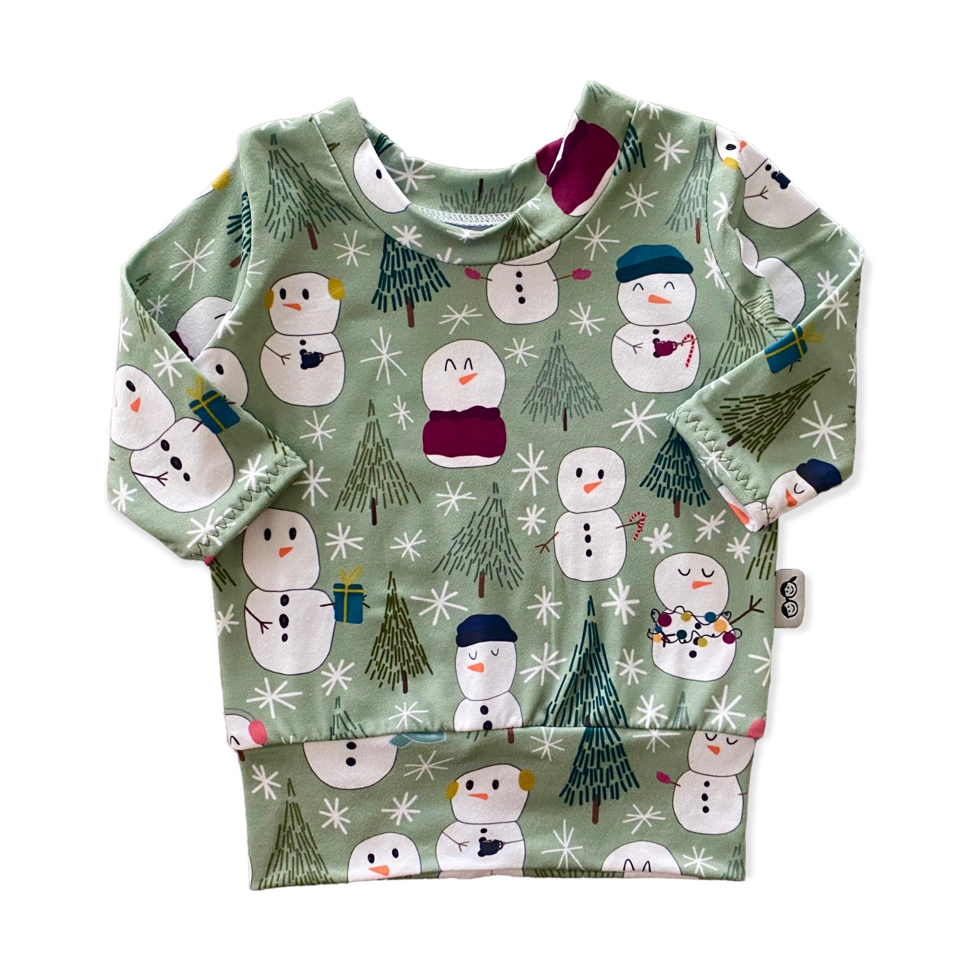 Snowman Print Lounge Set featuring a long-sleeve pullover and matching leggings with a playful snowman and winter tree design on a soft green background. Handmade for babies and toddlers, perfect for holiday celebrations and seasonal wear.