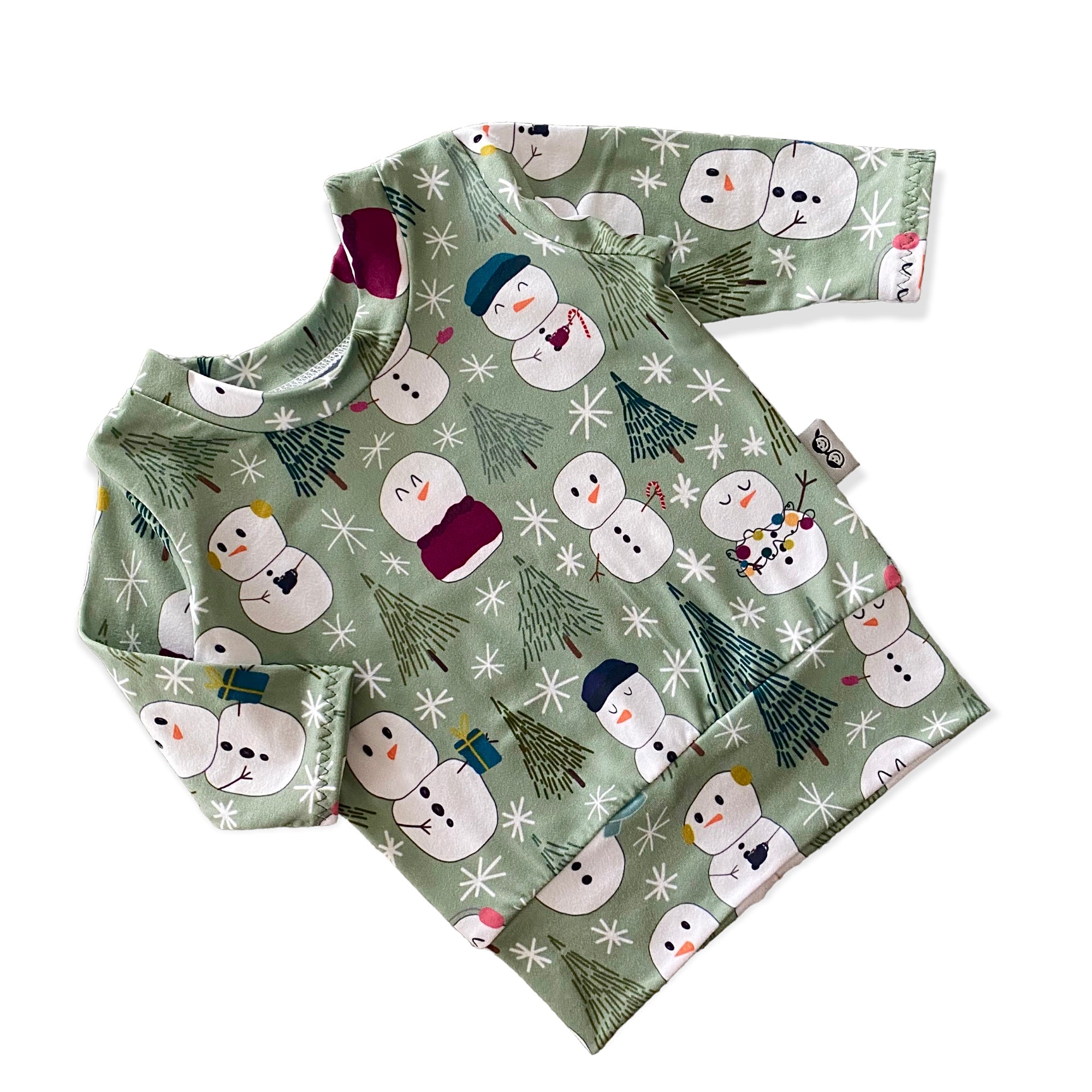 Snowman Print Lounge Set featuring a long-sleeve pullover and matching leggings with a playful snowman and winter tree design on a soft green background. Handmade for babies and toddlers, perfect for holiday celebrations and seasonal wear.