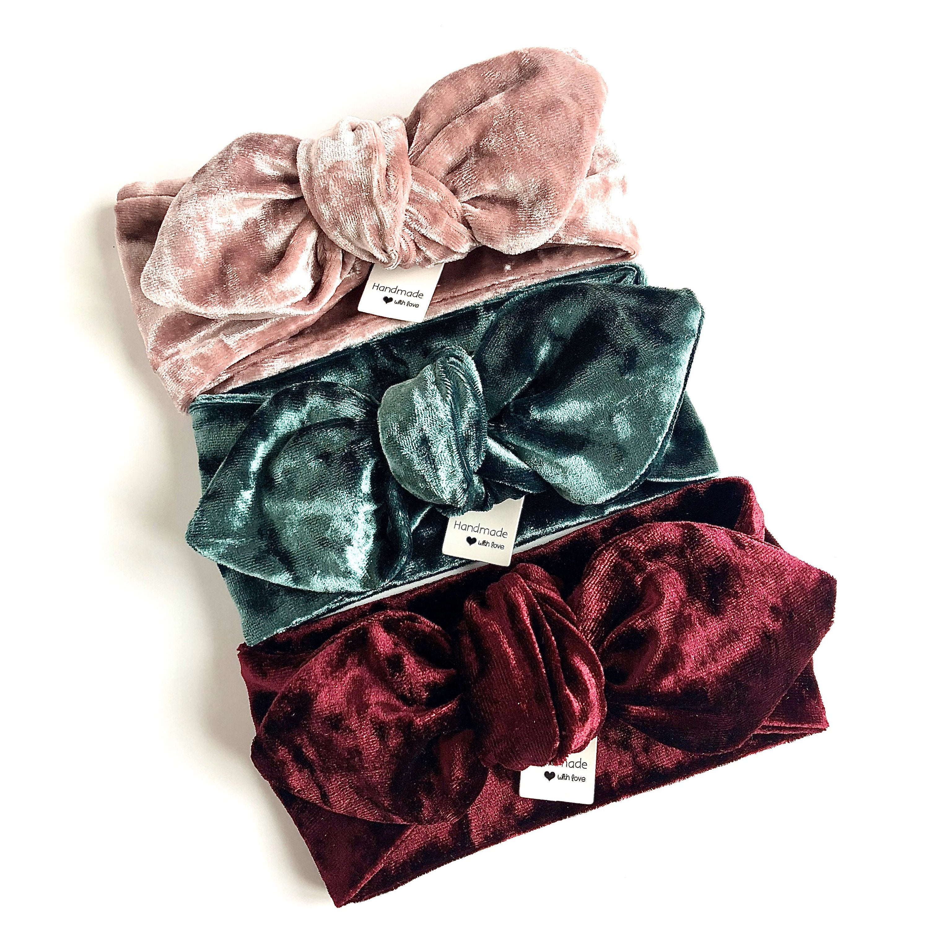 Set of three velvet bow turbans in blush pink, emerald green, and deep wine, featuring a knotted bow detail. Handmade for babies and toddlers, perfect for holidays, special occasions, or stylish everyday wear.