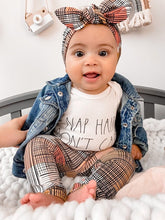 Adorable baby sitting in Retro Plaid Leggings paired with a matching plaid bow headband, denim jacket, and a &
