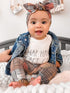 Adorable baby sitting in Retro Plaid Leggings paired with a matching plaid bow headband, denim jacket, and a &