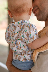 Back view of baby wearing a charming vintage rabbit print baby top, featuring adorable bunny and carrot illustrations. Perfect for Easter, springtime, and everyday play. Paired with soft, stretchy blue ribbed leggings. Handmade in sizes preemie to 4T.