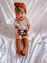 Child wearing a turban and holding an ultrasound image on a white background