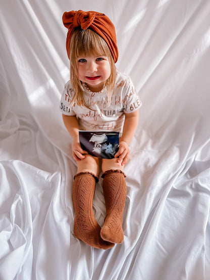 Child wearing a turban and holding an ultrasound image on a white background