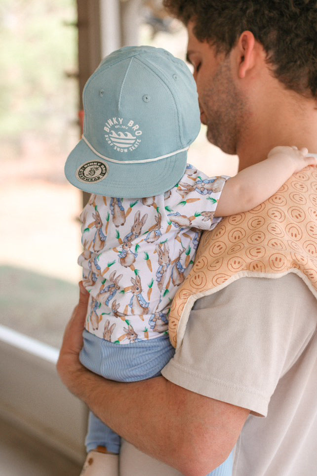 Adorable baby boy in a vintage rabbit print top and blue ribbed leggings, paired with a stylish cap. A timeless and gender-neutral outfit perfect for spring, Easter, and everyday play. Handmade from breathable, soft cotton-blend fabric.