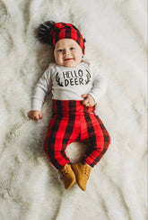 Adorable baby wearing red buffalo plaid leggings and matching beanie with &