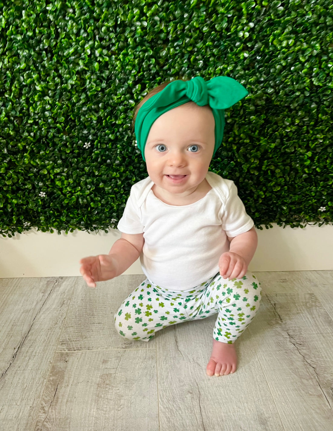 Baby Girl in festive green shamrock print leggings paired with a matching knotted headband, perfect for St. Patrick&