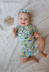 Baby in a floral lounge set on a textured surface with a &