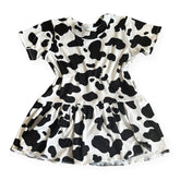 Girls cow print dress in black and white with short sleeves and gathered skirt, handmade toddler outfit perfect for birthdays or farm-themed parties.