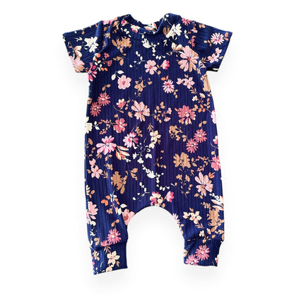 Navy ribbed baby romper with pink, mauve, and tan floral print – short sleeves and cuffed legs, laid flat.
