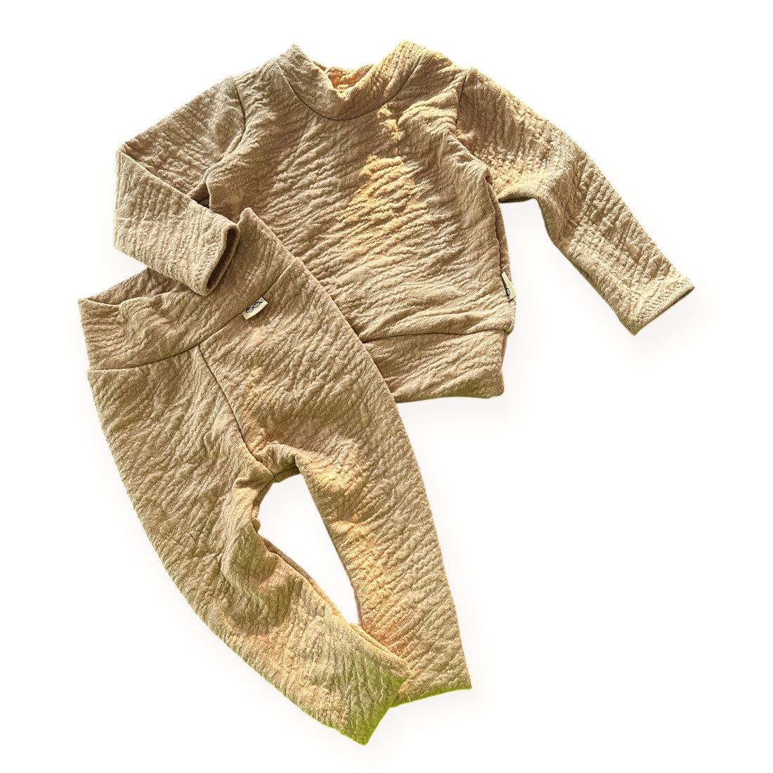 Beige textured sweater and pants set on a white background