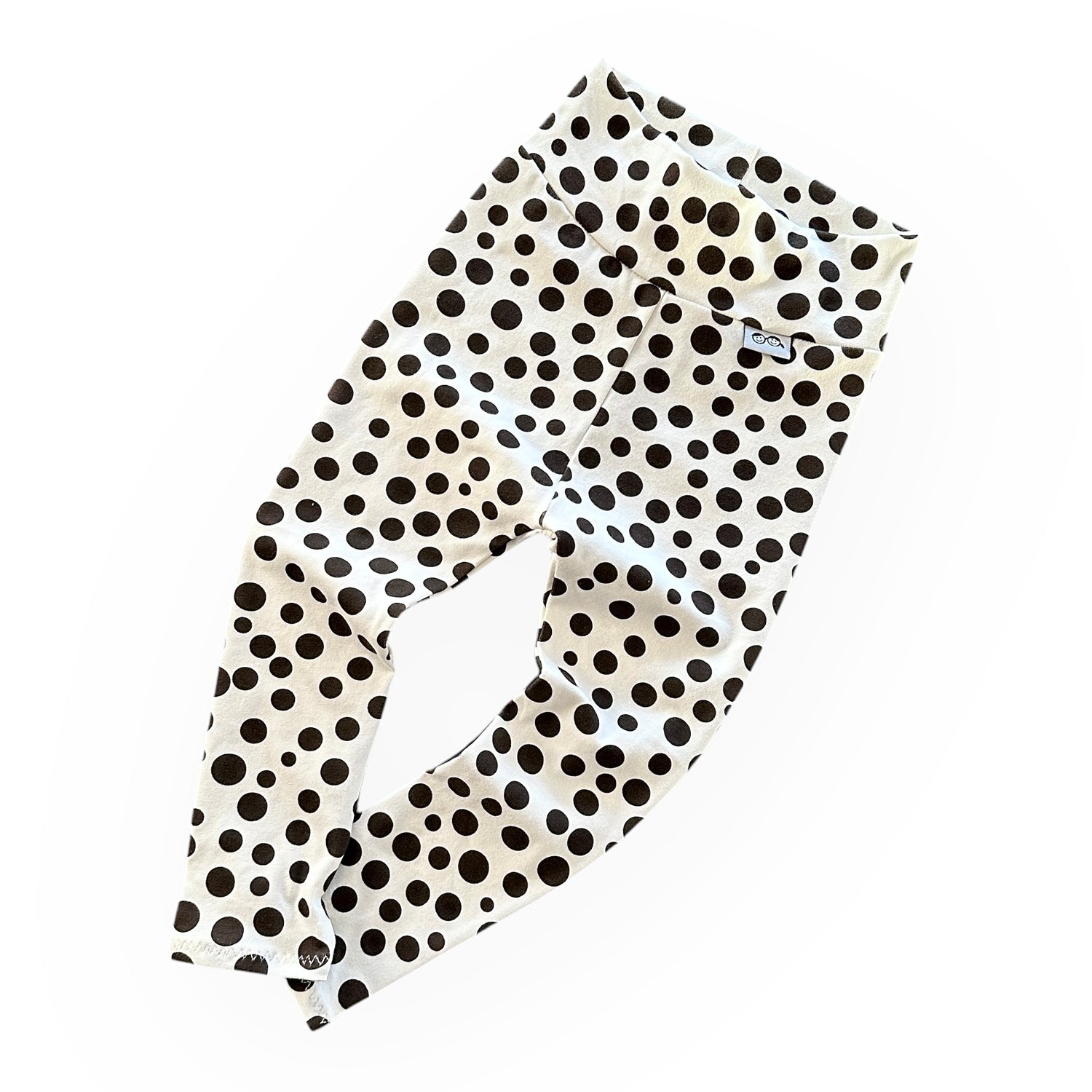 Baby leggings in white with bold black polka dots, featuring a soft high waistband. Comfortable and stylish handmade baby pants for everyday wear.