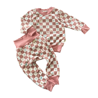 Flat lay of mauve checker smiley icons baby lounge set with top and pants.