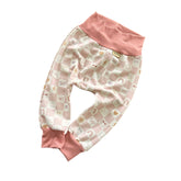 Side view of blush checker smiley baby lounge pants with ribbed cuffs.