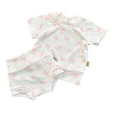 Baby outfit with short-sleeve top and shorts featuring pink bow pattern on a white background