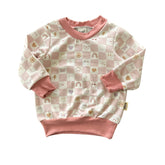 Front view of baby sweatshirt in blush checker smiley print with ribbed trim.