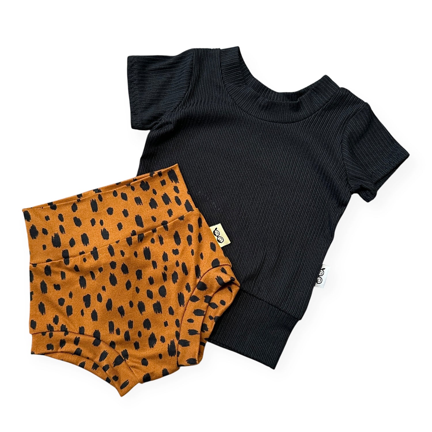 Black short-sleeve top and tan bummies with black spots on a white background