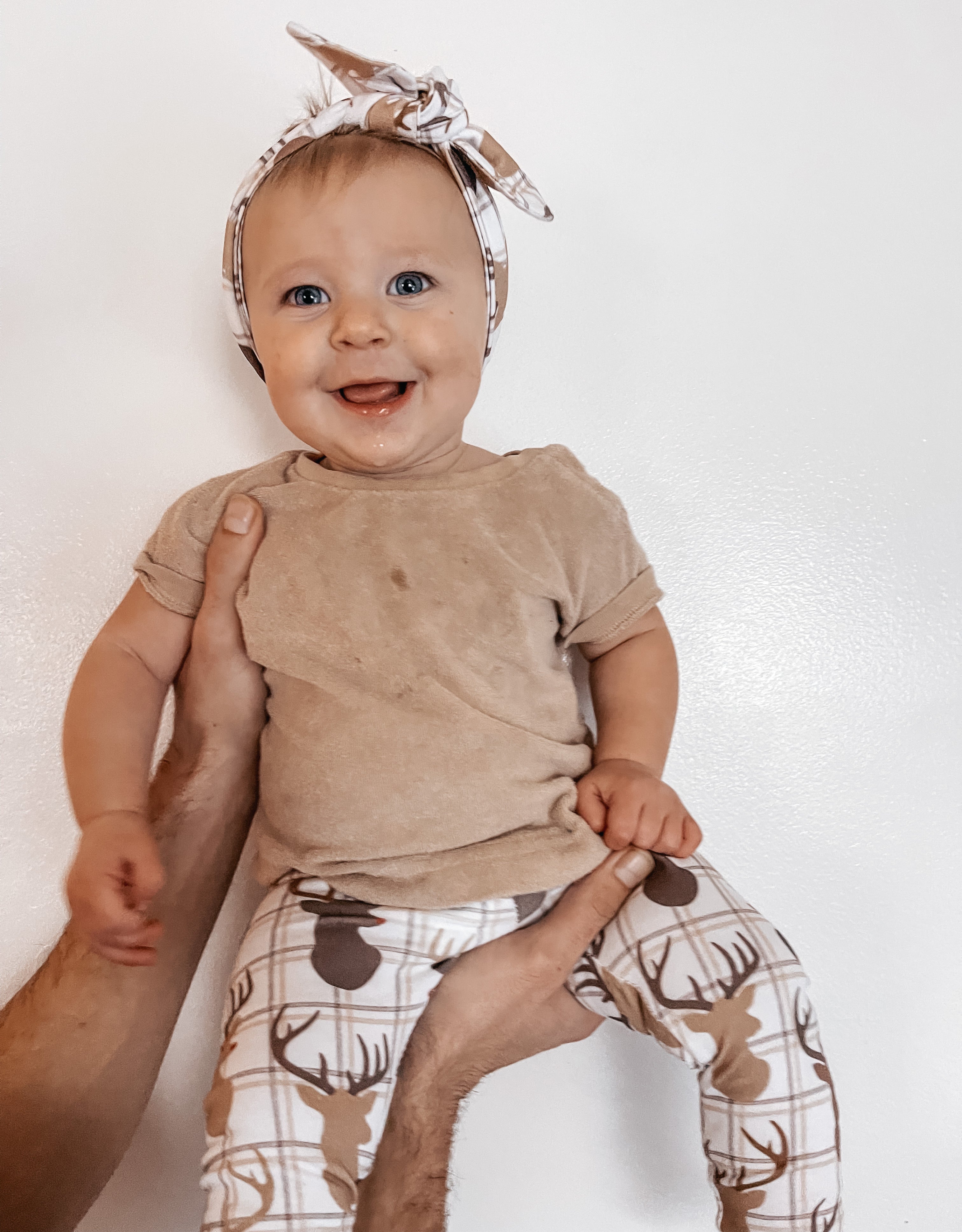 Smiling baby wearing handmade reindeer plaid leggings and a matching headband, perfect for cozy winter and Christmas outfits.