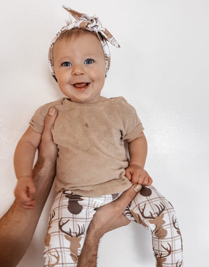 Smiling baby wearing handmade reindeer plaid leggings and a matching headband, perfect for cozy winter and Christmas outfits.