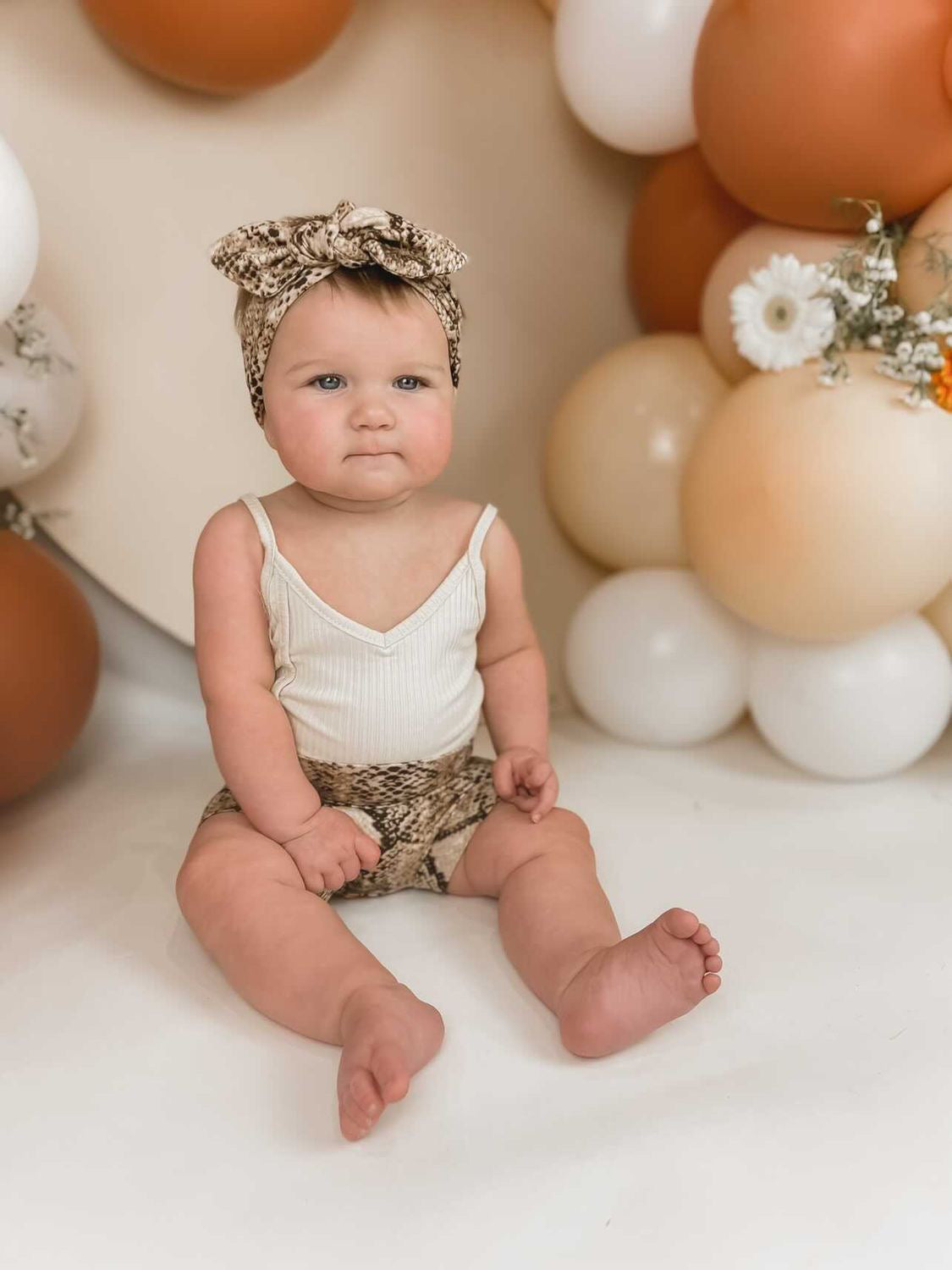 Baby Girl in Tan Snake Print Bummies 