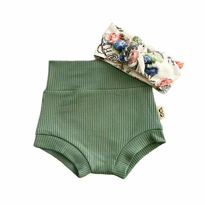Sea Spray Ribbed Bummies in a soft green hue paired with a white floral bow headband, perfect for a stylish and comfortable baby girl outfit.