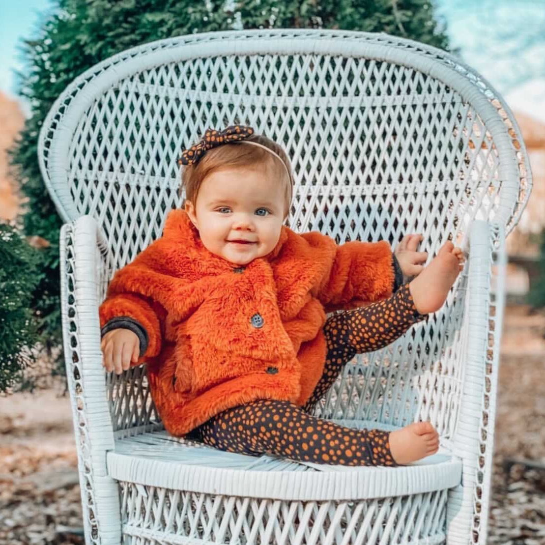 Baby sitting on a wicker chair wearing Black Abstract Micro Dot Leggings and/or Headbands
